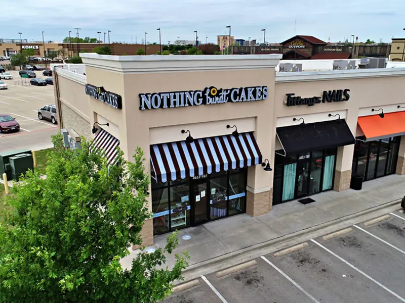 Exterior aerial view of multiple buildings and parking areas apart of Central Texas Marketplace