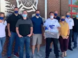 9 local business leaders in mouth masks posing for group photo outside fire station