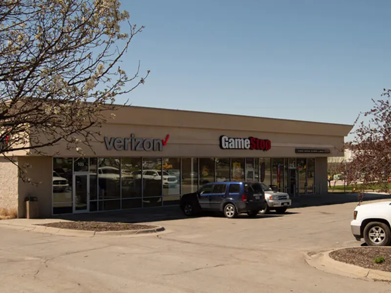 Exterior of front of Verizon and Game Stop buildings and parking area apart of Wolf Creek Plaza