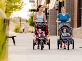 Two women walking their young children in strollers down Snake River Landing walkway