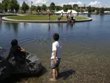 Young boys with feet in pond at Snake River Landing throwing rocks in water on sunny day