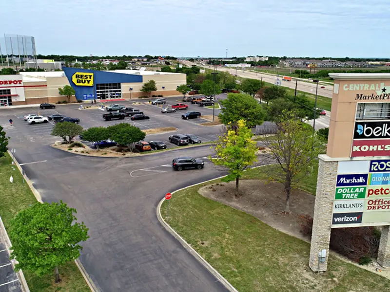 Exterior aerial view of parking area and multiple businesses within Central Texas Marketplace