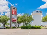 Exterior sign with multiple business logos behind parking lot in Mesquite