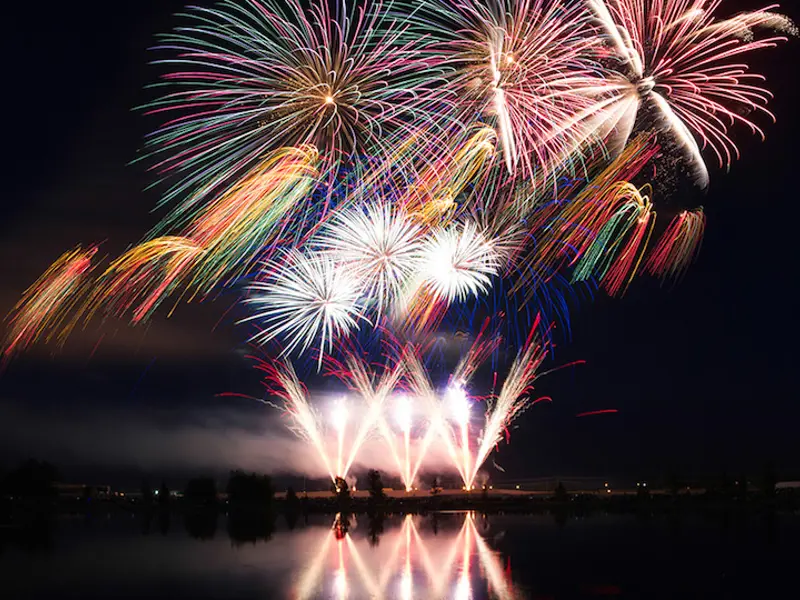 Night shot of multiple fireworks erupting from Snake River Landing during the Melaleuca Freedom Celebration