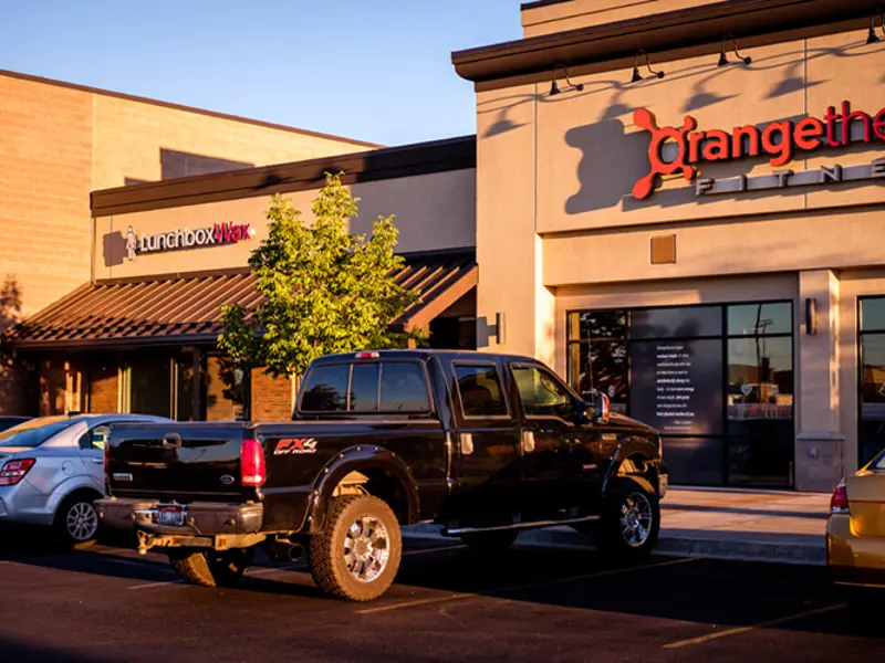 Exterior of front of Orange Theory building and cars at Sandcreek Commons