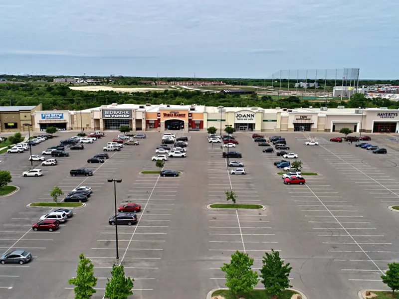 Exterior aerial view of multiple buildings and parking areas apart of Central Texas Marketplace