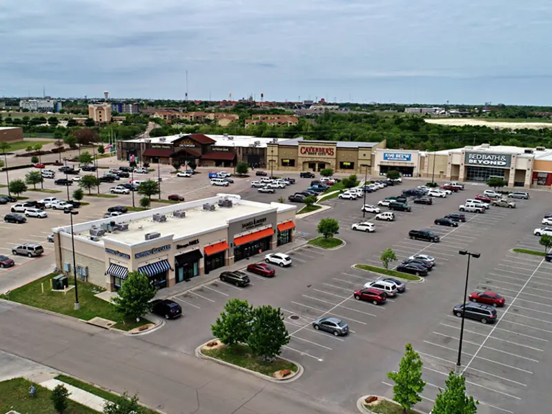 Exterior aerial view of multiple buildings and parking areas apart of Central Texas Marketplace
