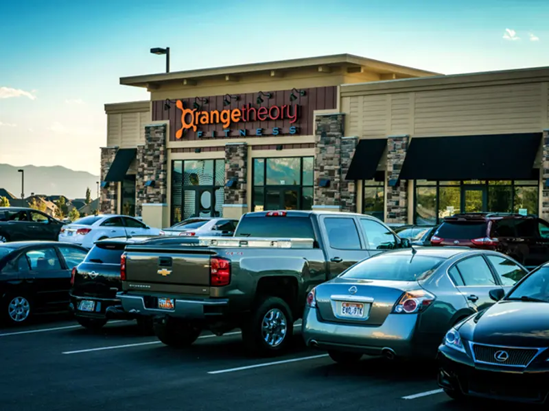 Exterior of parking lot and front of Orange Theory building at Center Pointe shopping center at dusk
