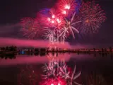 Nighttime red fireworks erupting over the Snake River in 2021 during the 2021 Melaleuca Freedom Celebration
